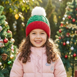 Close-up of red and green knitted Christmas hat with pompom on a child outdoors