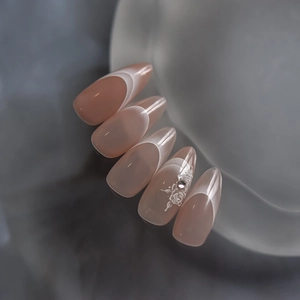 Detail of nude pink almond press-on nails with French gradient and rose floral patterns