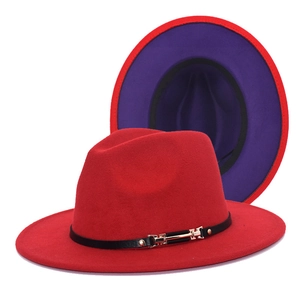 Detail view of red fedora hat with black leather band and golden buckle on wool felt