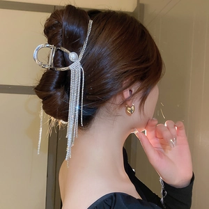 Gros plan d'une pince à cheveux argentée avec perles et longs glands en strass