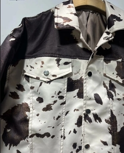 Dettaglio della giacca con stampa mucca, trama satinata e bottoni in metallo