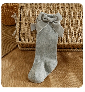 Detail of gray knit baby knee-high sock featuring a large shimmering silver velvet bow