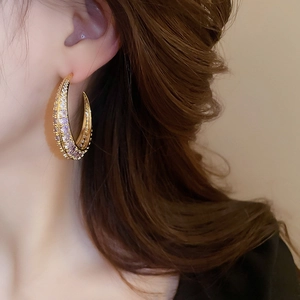 Macro shot of gold-plated crescent earrings set with purple and white cubic zirconia