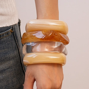 Makroaufnahme eines 4er-Sets dicker Harzarmbänder in Bernstein, Beige und Transparent