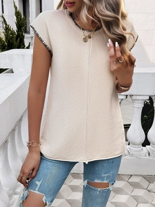 Detail of beige textured knit top with black contrast trim on cap sleeves and round neck