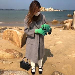 Detail of green ribbed knit gloves with touch screen design worn on a sunny beach