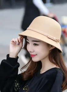 Dettaglio di un elegante cappello a secchiello in lana beige con fiocco sulla modella