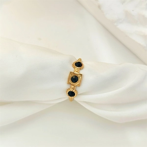 Macro detail of a gold ring featuring three black gemstones and vintage embossed textures