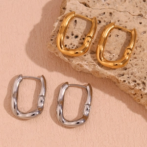 Detailed view of gold and silver irregular U-shaped hoop earrings on natural stone