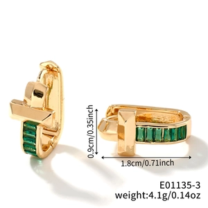 Detail view of gold U-shaped earrings with green zircon cross design and size measurements