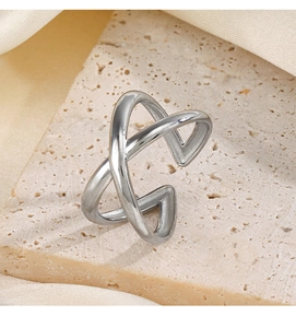 Detailed view of silver criss-cross open ring on a stone base with beige silk fabric