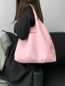 Detail of pink Simplicity canvas tote bag carried by a model against a grey wall