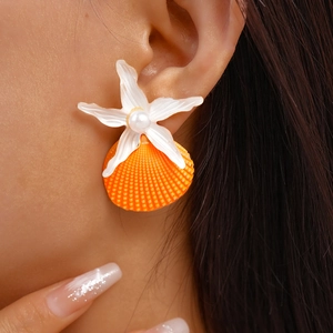 Detail shot of ocean-style earring featuring white starfish, orange shell, and a pearl