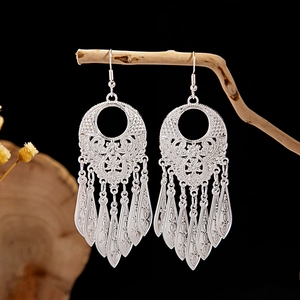 Macro shot of silver ethnic leaf earrings with hollow patterns and three-layer tassels
