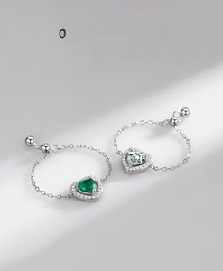 Gros plan de bagues en chaîne d'argent S925 avec zircons en forme de cœur vert et blanc