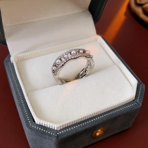 Macro detail of wave-shaped silver ring with pearls and zircons in a jewelry box
