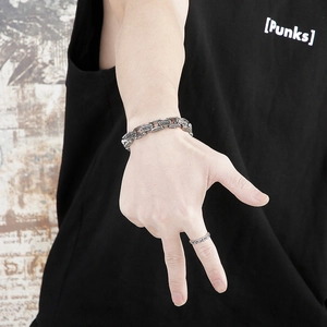 Close-up of vintage carved titanium steel bracelet and punk style ring on hand