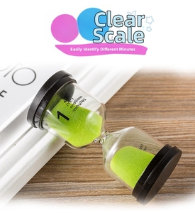 Detail of 1-minute green sand hourglass with black lids on a wooden desk surface