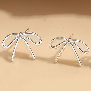 Close-up of minimalist silver bow stud earrings with a polished metallic finish