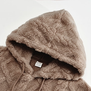 Macro detail of brown fleece hood texture and neck label showing material and size M