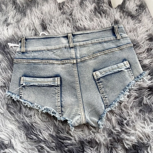 Dettaglio dei bordi sfrangiati e delle tasche posteriori di questi shorts di jeans azzurri