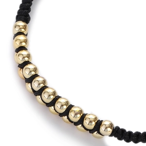 Macro shot of high-polish gold beads and black braided rope on a minimalist hip hop bracelet