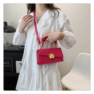 Gros plan du sac bandoulière rose avec boucle dorée martelée et poignée froncée