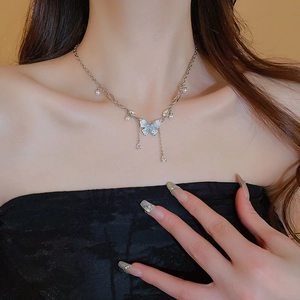 Primo piano di una collana a farfalla argentata con nappe di cristallo e perle su modella
