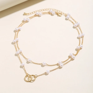 Close-up of double-layer gold chain with faux pearls and interlocking rings detail
