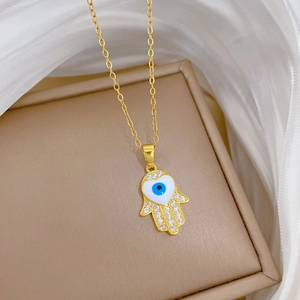 Detail of Hamsa Hand necklace with blue eye, white heart, and clear zircons in gold finish