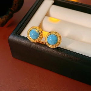 Detail of vintage 18k gold plated turquoise stud earrings on a jewelry box liner