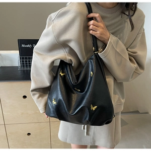 Close-up of black PU leather tote bag with 3D golden butterfly metallic ornaments