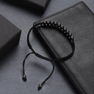 Hip hop black beaded braided bracelet with adjustable cord on premium leather surface