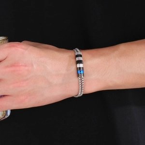Détail du bracelet chaîne hip-hop avec pendentifs cylindriques argentés, noirs et bleus