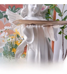 Detail of white resin angel statue holding a gold metal tray for entryway storage