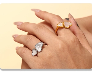 Detail of geometric double heart rings in gold and silver with natural mother of pearl