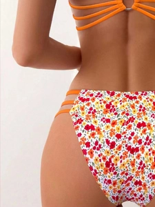 Detail of floral bikini bottom with orange side cut-out straps and high-stretch fabric