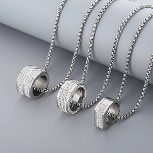 Detailed view of silver stainless steel chains with iced-out ring pendants on a display stand
