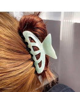 Detailed view of a light green mermaid tail hair claw with elegant pearls in hair