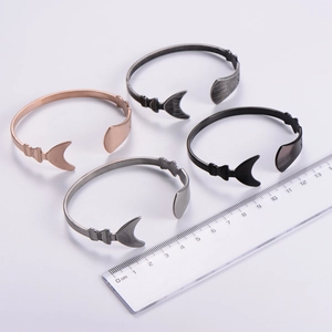 Detail of four irregular open bangles in rose gold, silver, matte black and gun grey