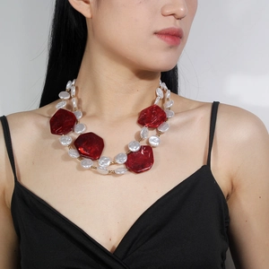 Close-up of double-layer necklace with red resin blocks and white flat pearls on a model