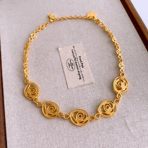 Macro detail of French vintage golden necklace featuring five hollow rose flower pendants
