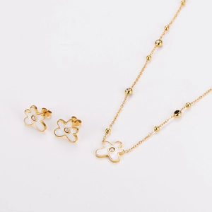 Close-up of golden stainless steel necklace and floral earrings with pearl centers