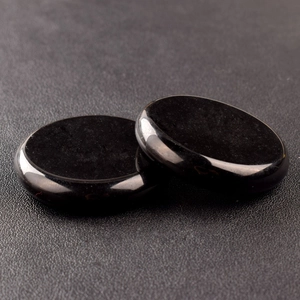 Close-up of two polished black round energy stones with smooth reflective finish