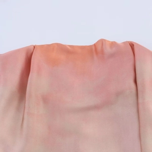 Gros plan détaillé du tissu satiné dégradé rose et orange avec une texture soyeuse