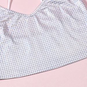 Detail of holographic sequin V-neck crop top fabric with sparkling silver grid texture