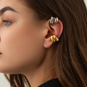 Macro shot of minimalist teardrop ear cuffs in gold and silver finish on model