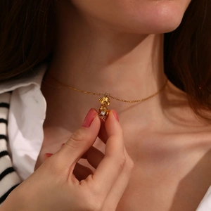 Close-up of a 18K gold plated dog pendant necklace with a small white diamond on a model