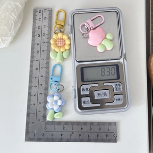 Detailed view of flower keychains with metal carbine on scale showing 8.30g weight