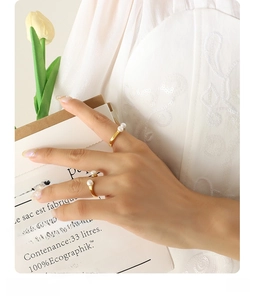 Detailed view of U-shaped gold rings set with natural pearls on a model hand